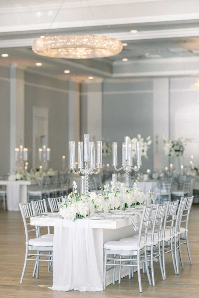 Newport Beach Wedding Venues | Brianna Graca Weddings Fine Art Wedding Photographer in Newport | Elegant banquet hall with white and silver decor, featuring long tables adorned with tall glass candelabras and white floral centerpieces. The atmosphere is sophisticated and serene.