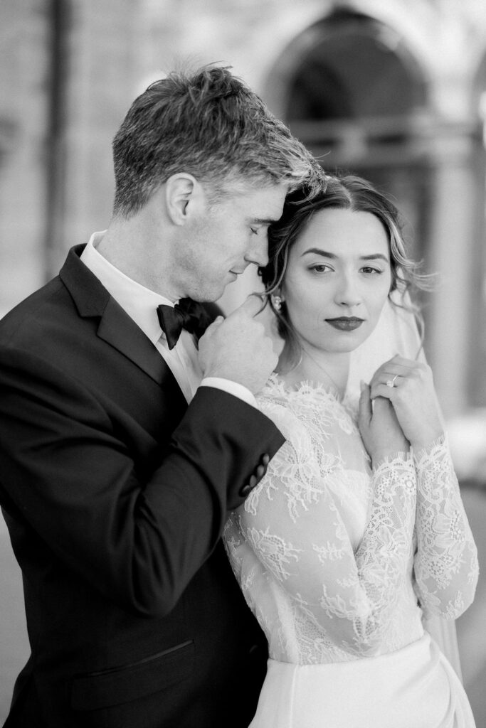 Wedding Photography RI | Brianna Graca Weddings Fine Art Wedding Photographer in Newport | Black and white photo of an elegant couple. The bride in a lace gown looks towards the camera, while the groom leans tenderly against her, exuding romance.