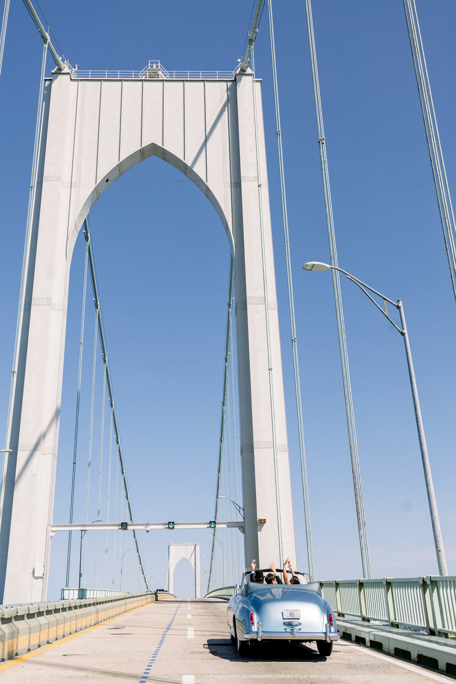 A baby blue vintage Rolls-Royce crosses the Newport Bridge on the wedding day.
