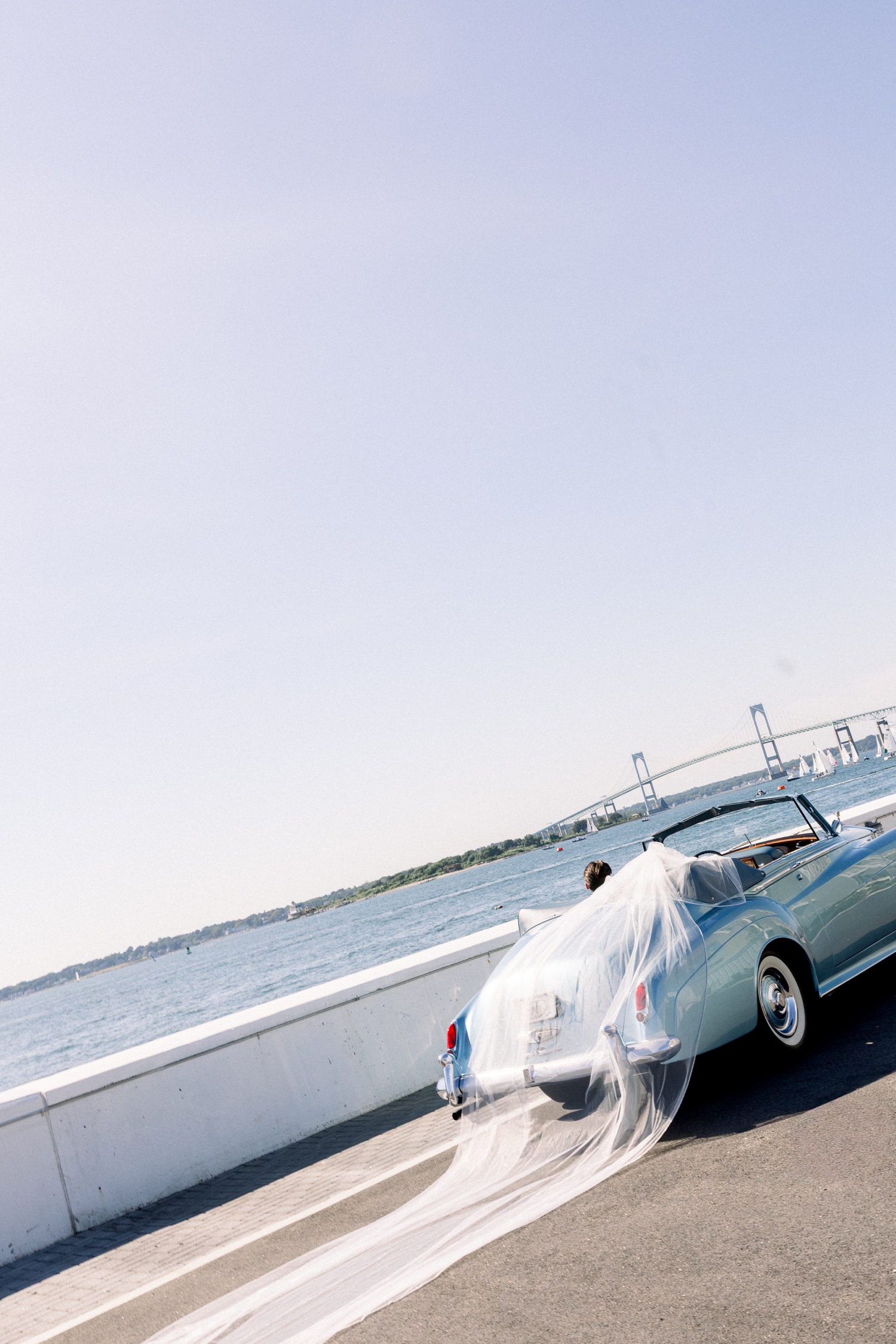A baby blue vintage Rolls-Royce crosses the Newport Bridge on the wedding day.