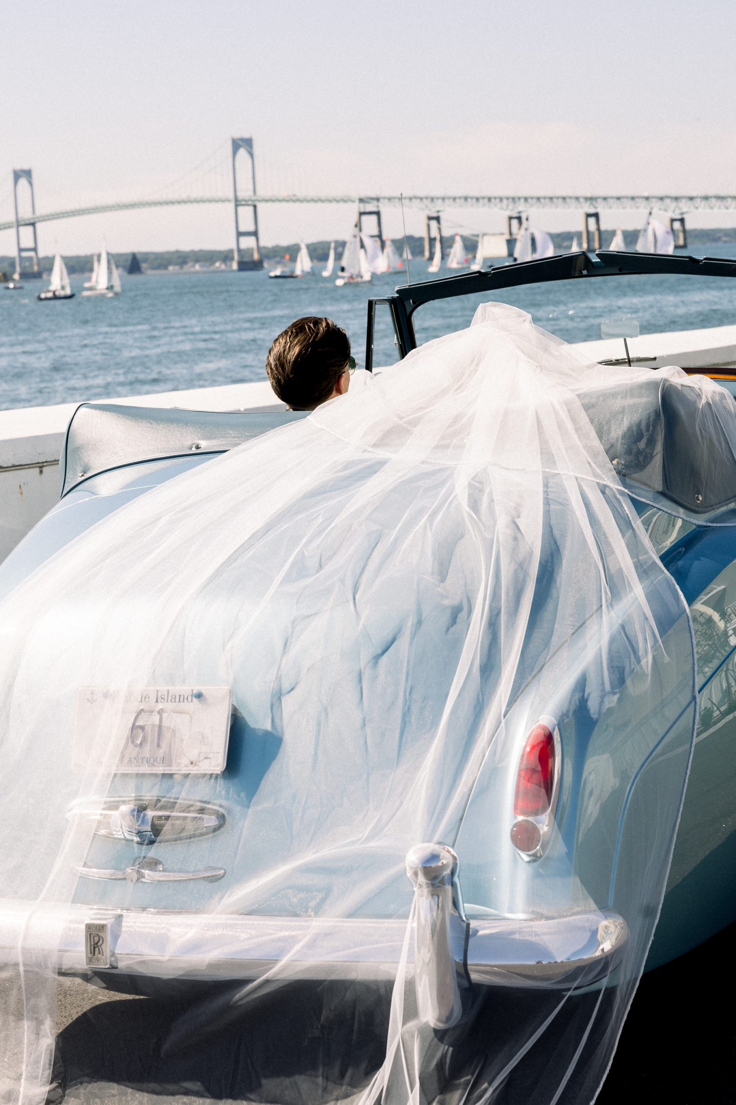 A baby blue vintage Rolls-Royce crosses the Newport Bridge on the wedding day.